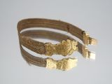 two gold bracelets on a white surface with a white background