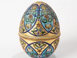 a blue and gold egg sitting on a white surface