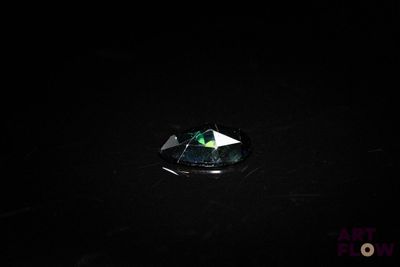 a close up of a green and white diamond on a black surface