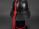 black helmet with red string tied to it on top of a black table