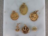 Des breloques et des pendentifs plaqués or sont exposés sur un socle en marbre