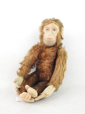 un singe en peluche assis sur une surface blanche