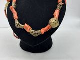 un collier orange et doré sur un mannequin noir