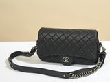 un sac Chanel noir avec une bandoulière en chaîne posé sur une table blanche