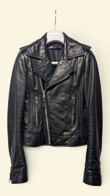 the leather jacket is hanging on a hanger on the wall