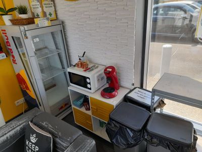 une petite cuisine équipée d'un micro-ondes, d'un réfrigérateur et de poubelles