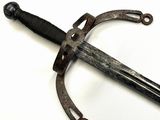 une épée d'aspect très ancien posée sur une surface blanche
