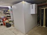 un réfrigérateur qui se trouve dans un garage, à côté d'une pile de cartons