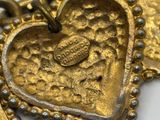 two gold heart shaped pendants on a white surface