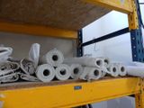 several rolls of white paper are stacked on a shelf in a warehouse