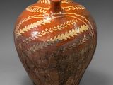 un vase marron orné de motifs sur un fond gris