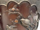 a metal vase with a bird and flower design on it