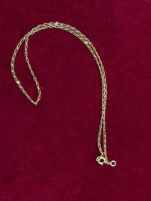 un collier en or avec une chaîne posé sur un fond de velours rouge