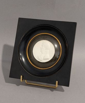 une assiette noire bordée d'or, dans laquelle se trouve une pièce de monnaie