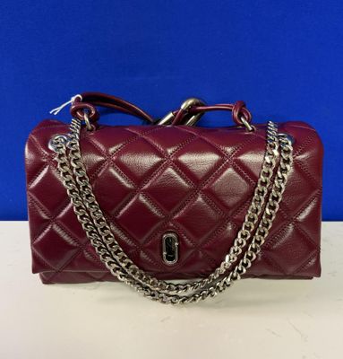 a red handbag with a chain strap on a white table