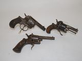 three old revolvers are sitting on a white surface