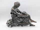 bronze statue of a woman sitting on a bench with her legs crossed