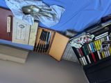 many books and pens on a bed with a blue sheet