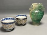 trois tasses posées à côté d'un vase sur une table