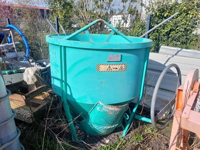 un grand seau bleu posé par terre à côté de quelques fûts