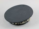 a close up of a black hat on a white surface