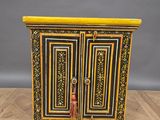 a black and gold painted cabinet on a wooden floor