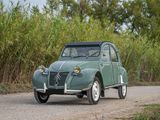 a small green car that is driving down a dirt road