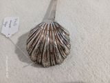 une cuillère en argent ornée d'un coquillage, posée sur une table