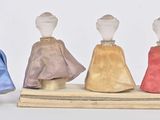 three miniature figurines of women dressed in different colors and sizes