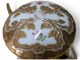 a close up of a gold and white vase with a flower on it