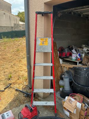 a ladder that is leaning against a wall next to a pile of junk