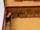 a brown suitcase with a mirror and a pen in it