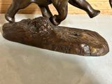 a bronze statue of a dog running on a log