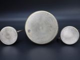 three pieces of silver are sitting on a black surface