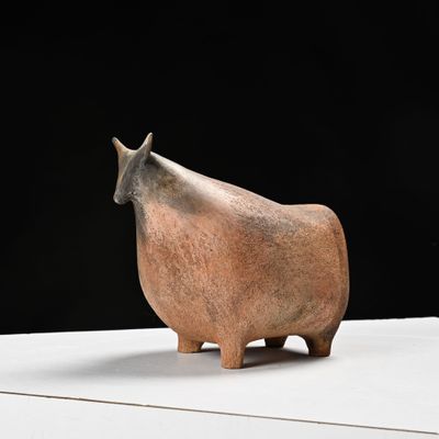une petite statue représentant une vache assise sur une table