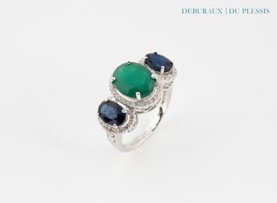 un gros plan d'une bague sertie d'une pierre verte et de saphirs bleus
