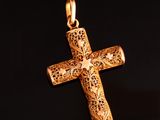 pendentif en forme de croix en or orné d'une étoile, sur fond noir