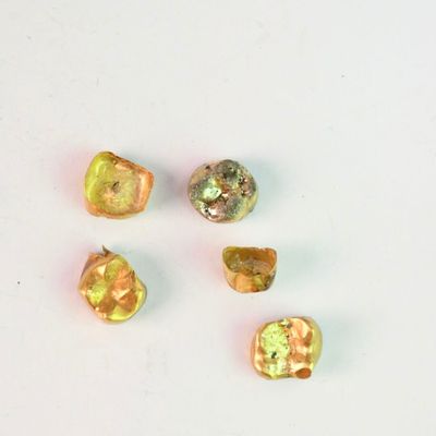 quatre perles de verre de couleur jaune et verte sur un fond blanc