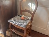 a wooden chair with a cushion on it in the corner of a room
