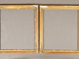 two gold framed mirrors on a wall above a mirror