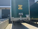 a green semi truck that is parked in front of a building