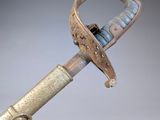 a very old sword with a metal handle on a gray surface