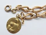 a close up of a gold chain with a coin on it