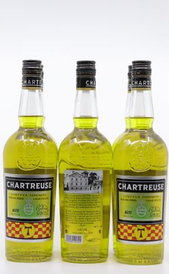 trois bouteilles de Chartreuse sont alignées sur une surface blanche