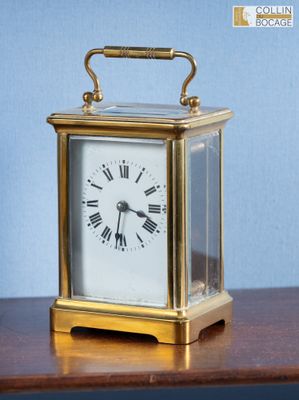 une petite horloge posée sur une table en bois, avec un mur bleu en arrière-plan