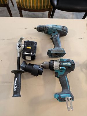 two corded drillers and a hammer are sitting on a table