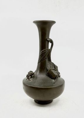 un vase noir orné d'un oiseau sur fond blanc