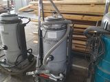 two vacuums that are sitting next to a pile of wood