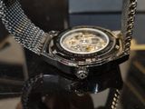 a watch sitting on a glass table with a chain around it