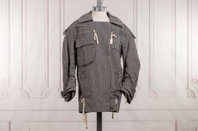 un manteau rayé noir et blanc posé sur un pied de mannequin